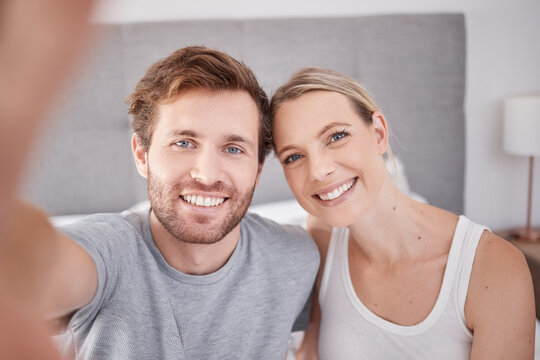 A selfie in bedroom of man and woman as couple. Portrait of young, happy and smiling people taking a picture together in the morning and wearing pajamas. Taking a photo with smile, bonding and love