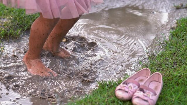 piernas de ni&ntilde;a festejando celebrando en parque brincando en charco con agua de lluvia y lodo con tierra sucia disfrutando y divertida en el parque al exterior al aire libre en un hermoso d&iacute;a