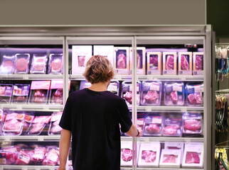  Man choosing frozen food from a supermarket freezer., reading product information