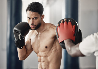 Fitness, training and a man boxing in gym with personal trainer and sparring pads. Health,...