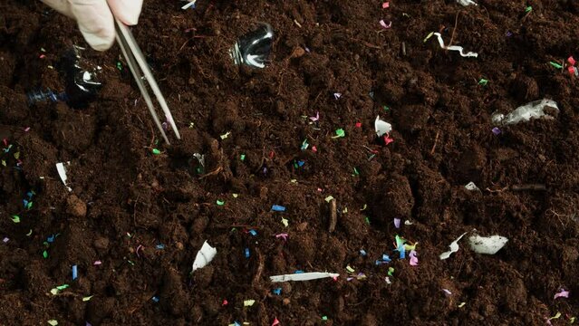 Microplastic earth pollution, plastic particles in soil close-up, cleaning ground from garbage and trash, environmental ecological problems. Global warming and climate changing.