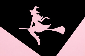 witch on broom on black part of black and pink background, creative art design, halloween minimal concept
