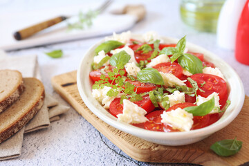 Vegetarian cuisine. Tomato salad with mozzarella and basil, olive oil and pepper dressing