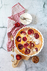 Red plums clafoutis (flan) with almonds, icing sugar dressing, french cuisine