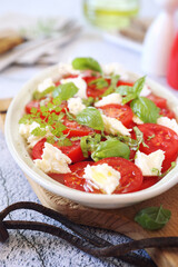 Vegetarian cuisine. Tomato salad with mozzarella and basil, olive oil and pepper dressing