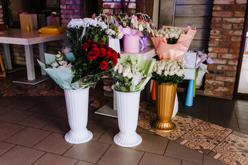Many white vases with multi-colored flowers in the package are in the interior of the restaurant.