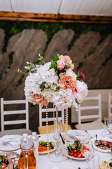 Beautiful multi-colored flowers in a glass vase are on the table. Wedding decorations, photography.
