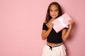 Picture of happy little girl child standing isolated over pink background. Looking camera holding...