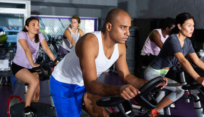 Fototapeta na wymiar Portrait of sporty man training on stationary bike in gym