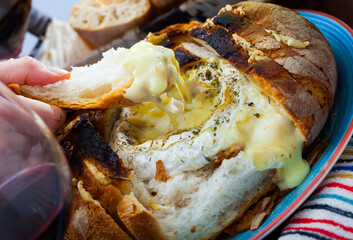 Rustic style cheese fondue made of camembert in hollowed out bread bowl
