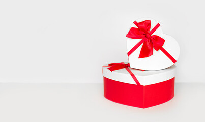 heart shaped present gift boxes with red ribbon and bow on light background with copy space