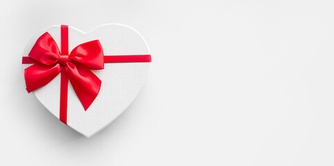 banner of heart shaped present gift box with red ribbon and bow on light background with copy space