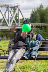 Fototapeta premium Father and son play with a ball on a bench in autumn. Entertainment with parents. Happy family on the street.