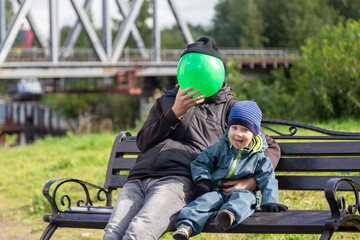 Father and son play with a ball on a bench in autumn. Entertainment with parents. Happy family on the street.
