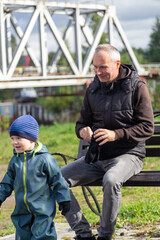 Father and son play with a ball on a bench in autumn. Entertainment with parents. Happy family on the street.