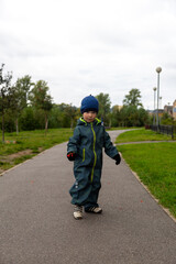 Fototapeta premium A two-year-old boy in autumn on the road with a rowan branch in his hands smiles on the street
