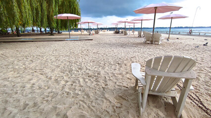 Adirondack chairs with pink umbrellas at the beach in the city