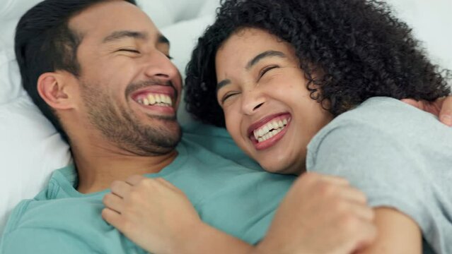 Happy, love and laugh with a couple laughing at a funny joke with a smile and bonding together in the bedroom of their home. Humor, romance and bed with a young man and woman enjoying time off