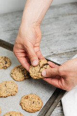Close up of male hand breaking freshly baked oatmeal raisin cookie in half, healthy, traditional and popular American biscuit recipe made of flour, sugar, eggs, rolled oats, dried fruit, baking soda - 531551135