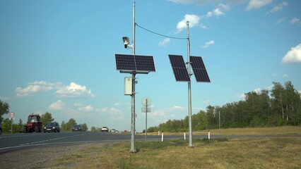 Solar panels on two poles in the steppe near the road. Camera for fixing traffic violations.