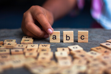 English alphabet made of square wooden tiles with the English alphabet scattered on table. The...