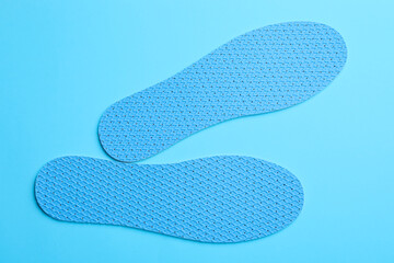 Pair of breathable shoe insoles on light blue background, flat lay