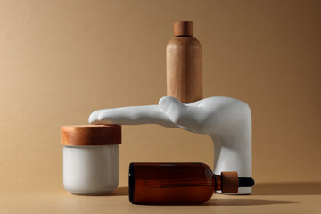 Bottles and jar of cosmetic products on dark beige background