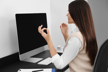 Young businesswoman meditating at workplace. Zen concept