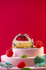 cake with raspberry filling cut and raspberries on a pink podium on a bright red background.Delicate airy cake souffle.Choux pastry.