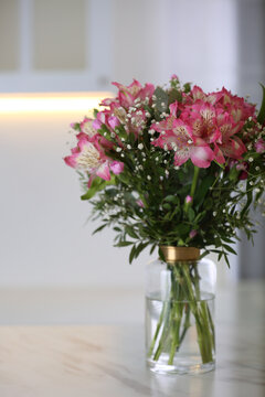 Vase with beautiful alstroemeria flowers on table in kitchen. Interior design