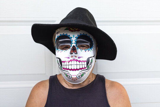 Portrait of an elderly lady with a catrina mask and hat, celebrating Halloween and All Souls' Day, on a white background. Celebration, costume, party and mask concept.