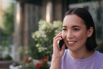 Portrait of smiling asian woman talking on mobile phone looking away, copy space