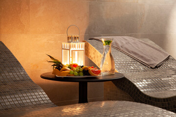 Sauna couch bench at stone walls interior with candle light standing lamp.