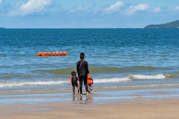 Mom and children walk along the edge of the sea at low tide in sunny weather. Thailand. City beach Pattaya. 