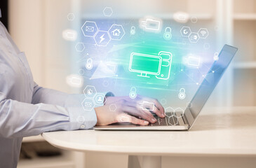 Hands working on laptop with digital icons