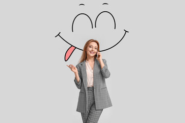 Stylish mature businesswoman talking by phone and drawn smile on light background