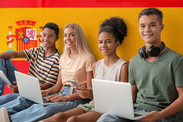 Students with modern devices against flag of Spain