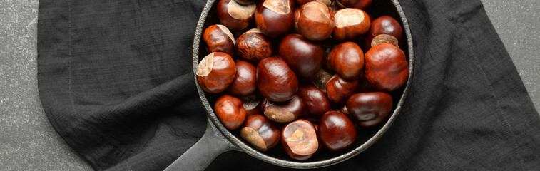 Frying pan with chestnuts on dark background, top view