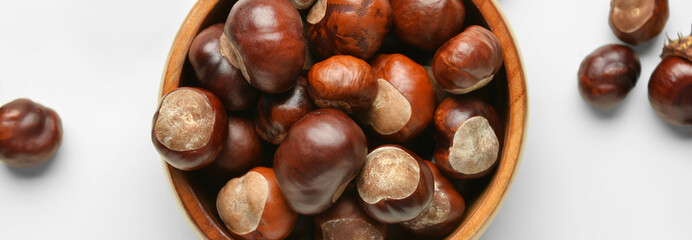 Bowl full of chestnuts on light background, closeup