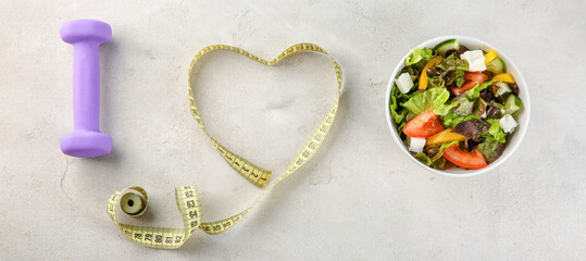 Vegetable salad, dumbbell and measuring tape on light background. Diet concept