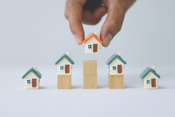 Real estate investors hold home models in hands. Saving plan to buy property, house. Personal financial concept for own a house. coin stack on wood table. copy space.