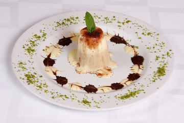 Banana dessert with custard and chocolate sauce on the dessert plate.