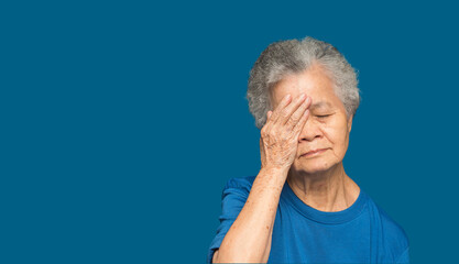Portrait of a senior woman with eye pain while standing on a blue background