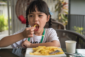 Asian girl eating french fries young kid fun happy potato fast food.