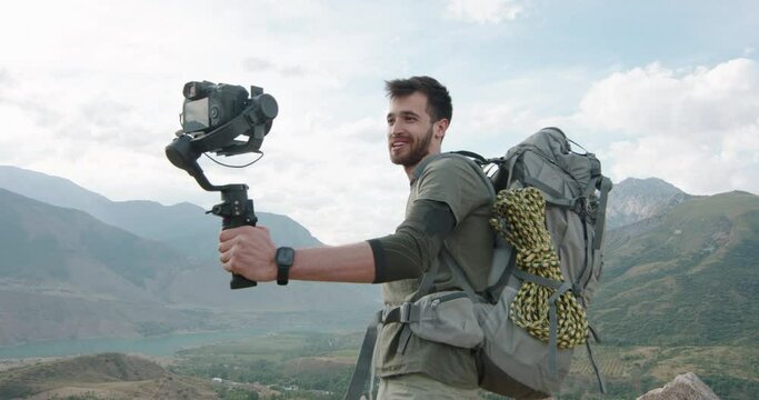 A young guy records a video message on camera shares travels adventures communicates with friends,demonstrates a real emotional connection a shoots a video blog enjoys a vacation in the mountains