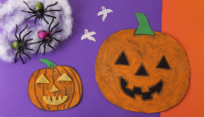 Calabazas de cartón pintadas a mano junto a grupo de arañas de plástico. 