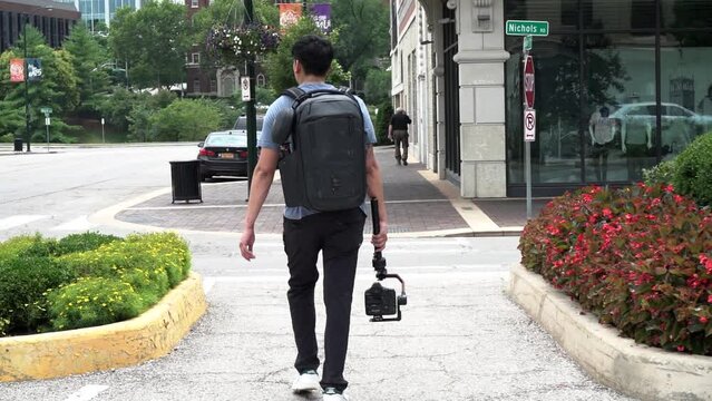 Filmmaker walks around the city with his camera and gimbal in hand.