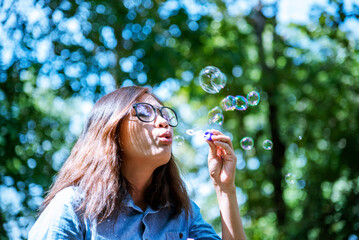 Happiness woman blowing soap joyful outdoors green park. Asian young women joy blow bubble leisure...