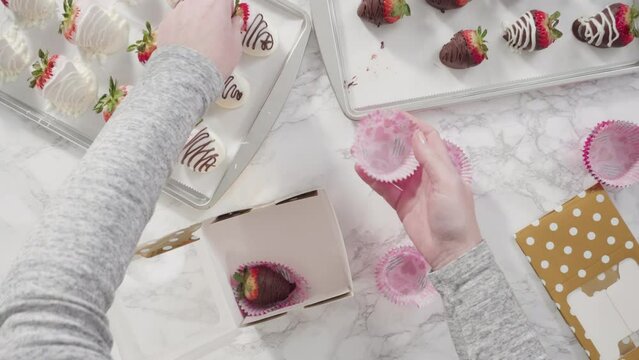 Flat lay. Step by step. Packaging chocolate dipped strawberries into a paper box for a gift.