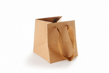 Square paper bag with cloth handles, partially folded. Over white background.